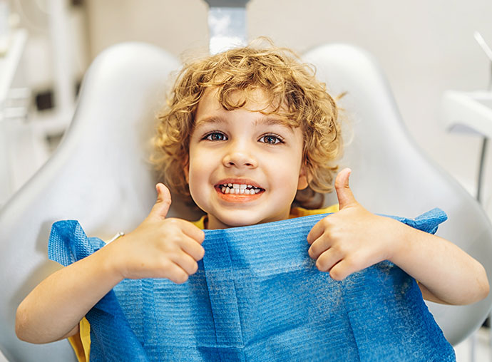 Smiling boy giving thumbs up after pediatric dental visit